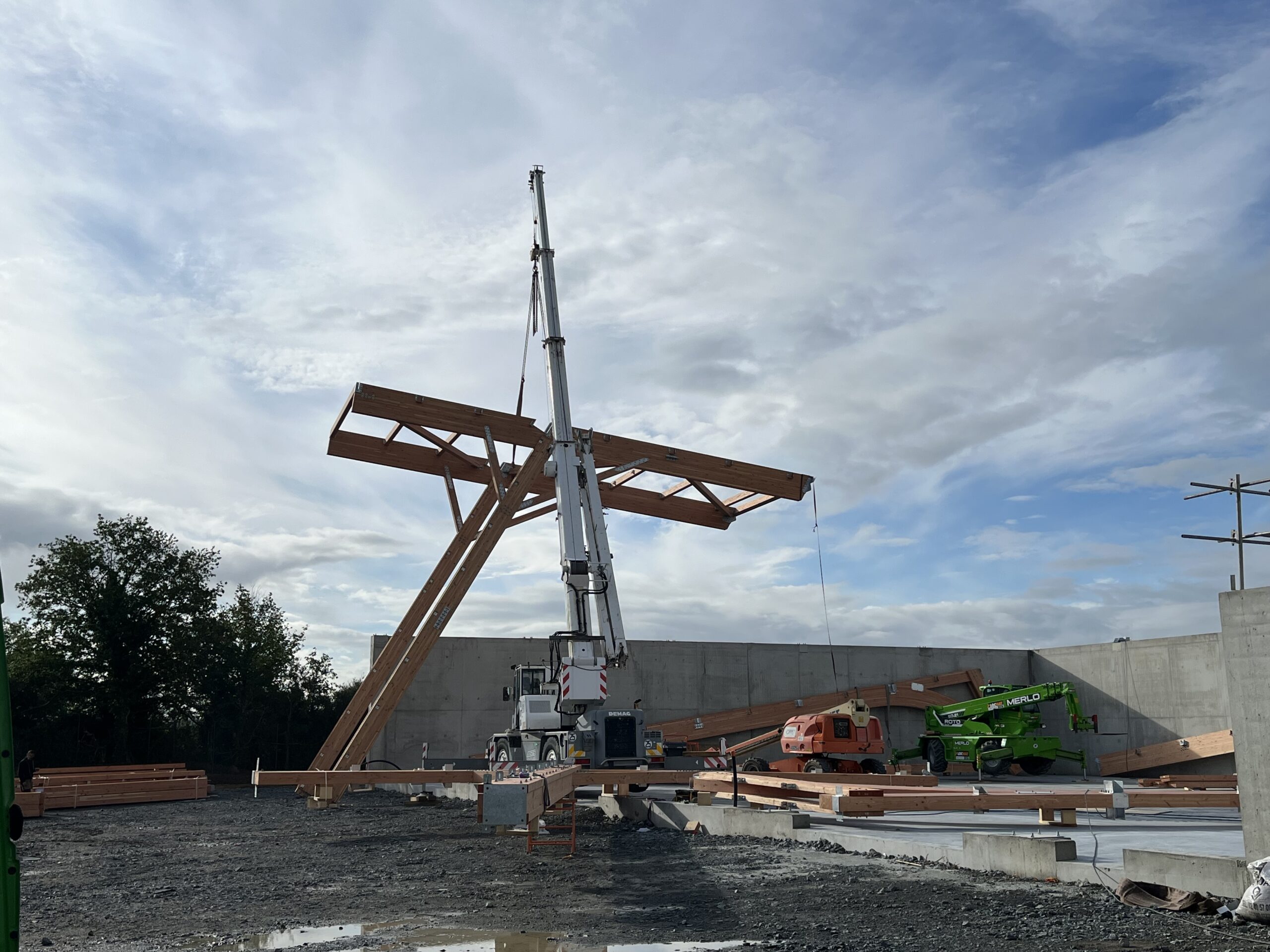 Un élément de structure bois levé par un manuscopique pour la pose de la charpente du quai de transfert