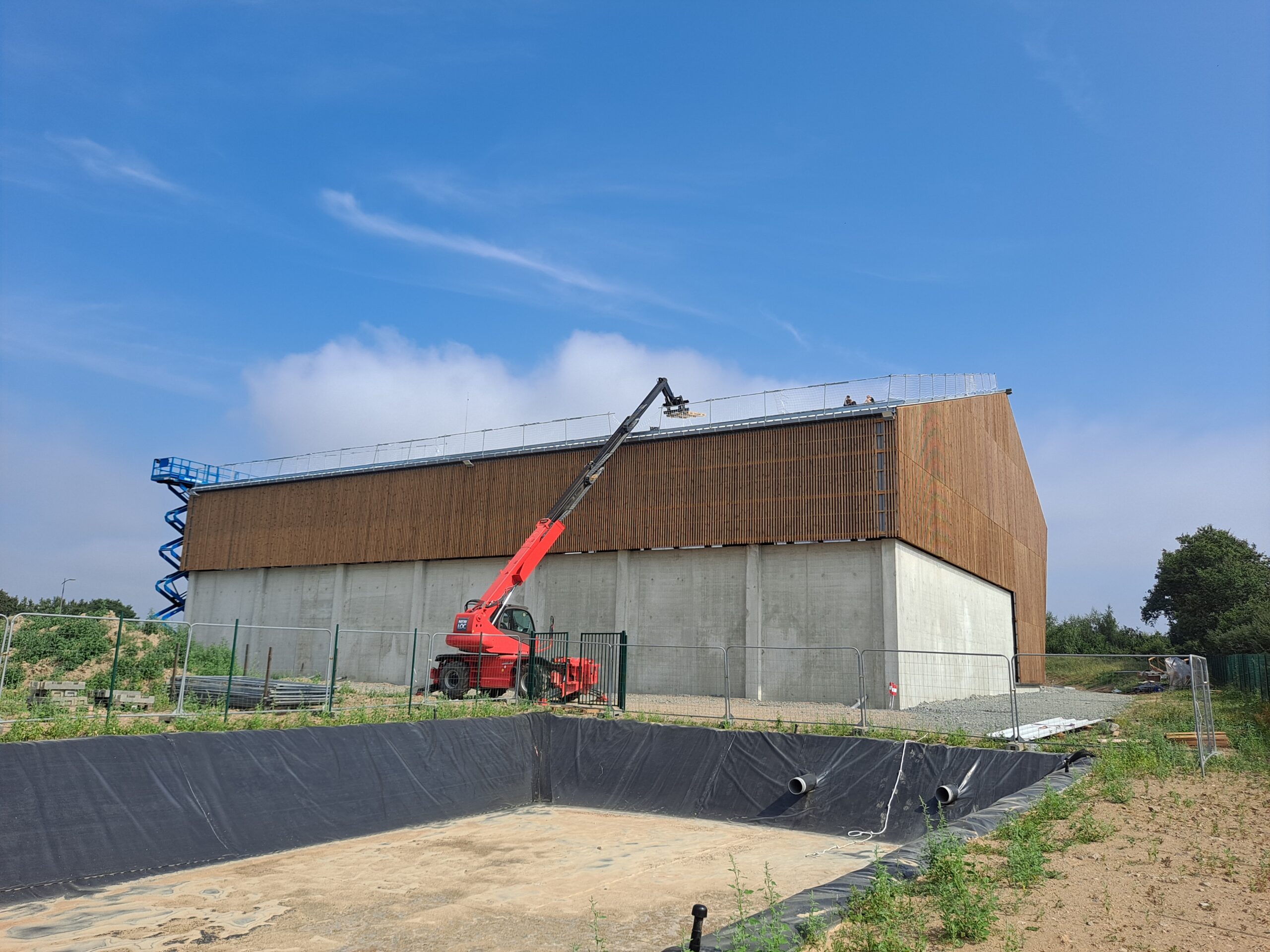 engin levage à l'arrière du bâtiment pour le début de la pose des panneaux photovoltaïques. 